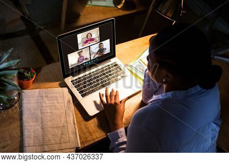 African american woman using laptop for video call, with diverse elementary school pupils on screen. communication technology and online education, digital composite image.