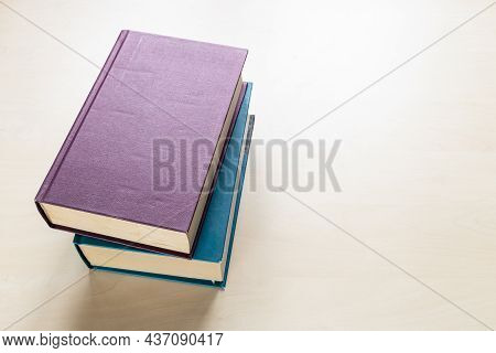 Top View Of Two Thick Volumes Of Books On Light Brown Wooden Board