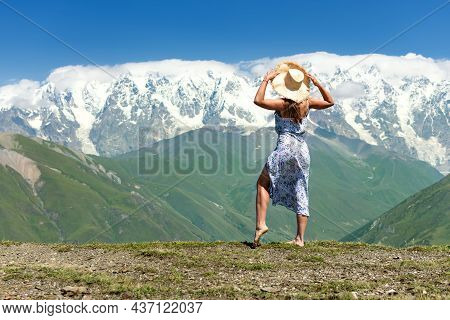 Young Beautiful Girl On The Edge Of A Cliff Looks At A Beautiful Mountain Landscape, Incredible View