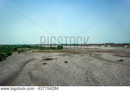 Wasteland Near A Cement Plant In Albania. An Empty Area With Vegetation Around The Perimeter. Backgr