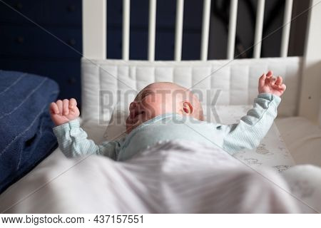 Crying Caucasian Baby On A Bed Suffering From Colic Pain.
