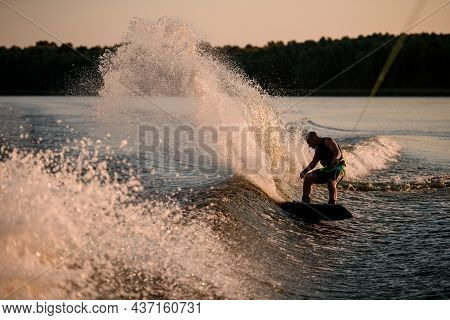 Active Man Energetically Rides Down On Splasing Wave On Wakesboard.