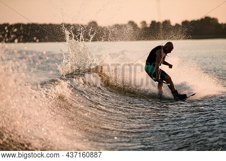Athletic Guy Holds Rope And Riding Wakeboard On Splashing River Wave.