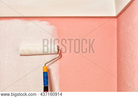 Close-up Of An Old Fleecy Paint Roller Painting Pink Paper On The Wall With White Paint Under The Ce