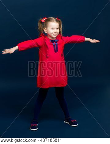 Cute Little Girl Standing With Her Arms Outstretched. Lovely Smiling Kid With Cute Two Ponytails Dre