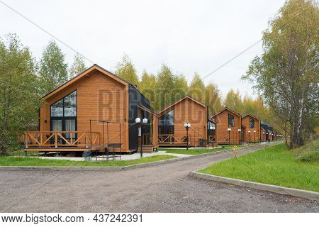 Street Of Modern Small Houses. Barnhouse Style Houses. The Houses Are Surrounded By Green Trees. Nat
