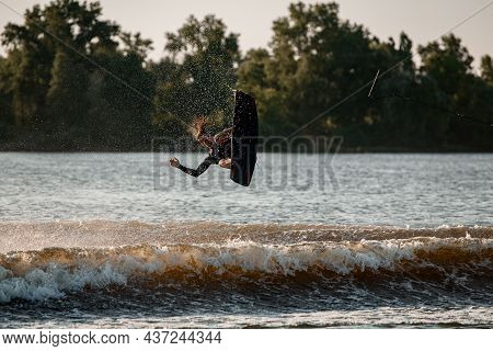 View Of Falling Active Male Wakeboarder With Wakeboard Over Water