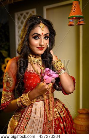 Portrait Of Pretty Young Indian Girl Wearing Traditional Saree, Gold Jewellery And Bangles Holding F