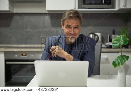 Portrait of businessman. Older man tele working with laptop computer at home office in living room.
