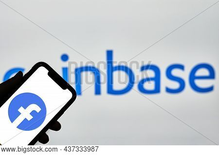 Tashkent, Uzbekistan - 22 October, 2021: Hand Holds Mobile Phone With Facebook Logo Over Coinbase Lo