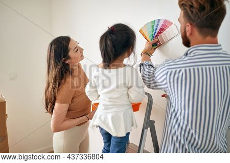 Happy multiethinc family painting walls together; Remodeling home concept