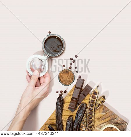 Organic Carob Pods, Powder, Chocolate And Carob Molasses On A Wooden Board In A Woman Hand On A Pink