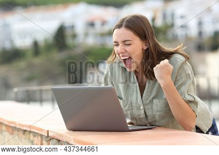Excited Woman Watching Media On Laptop Celebrating In A Coast