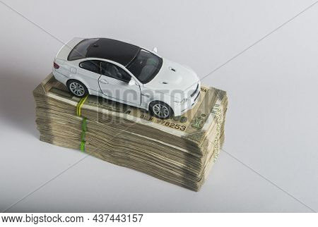 A toy car placed on the heap of Indian rupee bank notes. An idea for 'car loan' or 'Indian automobile market'
