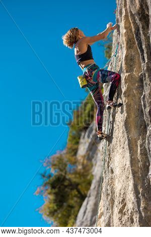 The Girl Climbs The Rock. The Climber Trains On Natural Terrain.  A Woman Overcomes A Difficult Clim