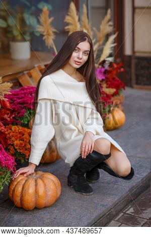 Fashionable Beautiful Young Girl In White Dress Sweater And Knee High Boots Is Sitting At The Autumn