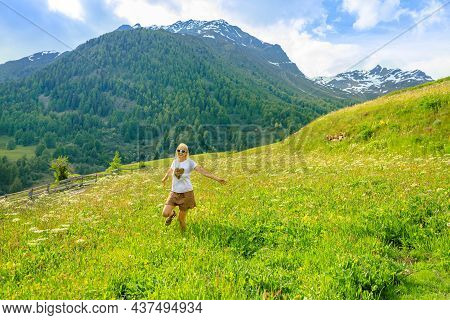 Happy Carefree Woman With A Short Skirt Running In The Countryside Of Guarda Village Of Scuol In Swi