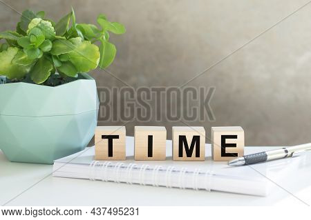 Time Text On Wooden Cubes On The Table Next To The Handle, Notepad Flower In A Pot On The Table In T