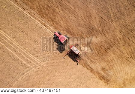 Agricultural Tractor Sowing Seed Onto At Field. Farming And Seeding Concept. Seeds Sowing In Farmers