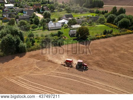 Agricultural Tractor Sowing Seed Onto At Field. Farming And Seeding Concept. Seeds Sowing In Farmers