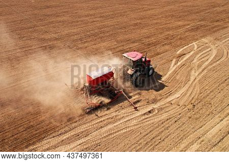 Agricultural Tractor Sowing Seed Onto At Field. Farming And Seeding Concept. Seeds Sowing In Farmers