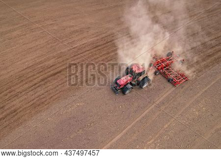 Soil Tillage In Farmers Country. Red Tractor On Cultivating Field Work. Agricultural Tractor On Cult