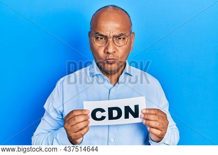 Middle age latin man holding cdn message paper skeptic and nervous, frowning upset because of problem. negative person. 