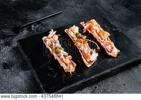 Crab Leg Meat In A Sheel With Herbs. Black Background. Top View