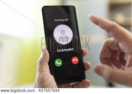 Unknown Caller. A Man Holds A Phone In His Hand And Thinks To End The Call. Incoming From An Unknown