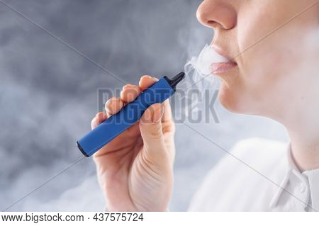 Caucasian Woman Smokes A Disposable Vape In The Studio.