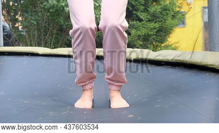 Young Woman Is Jumping On A Babut, A Close-up. Legs Float In The Air After Jumping On A Trampoline. 