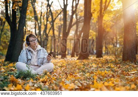 Caucasian Middle Aged Woman In Earphones Listening To Music, Meditation App On Smartphone And Medita