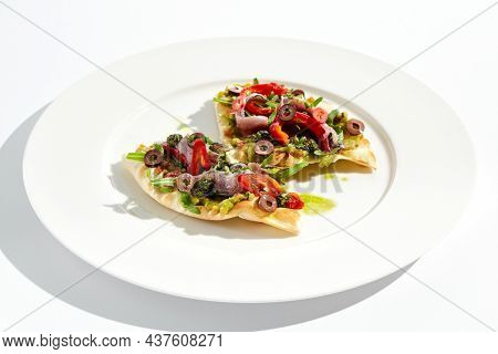 Tapas with avocado cream, anchovy, paprika and kalamata olives on focaccia. Bruschetta with guacamole and anchovy isolated on white background. Appetizer contemporary concept. Fish antipasti