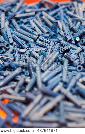 Dowels Wall Plugs Close Up. Plastic Blue Dowels On Red Background, Dowels For Fixation And Installat