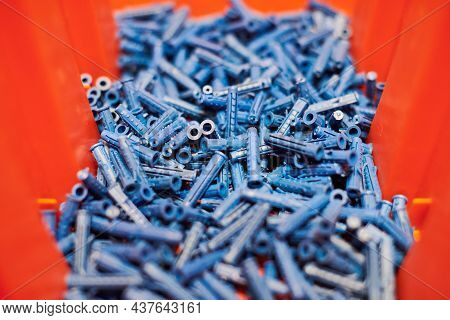 Dowels Wall Plugs Close Up. Plastic Blue Dowels On Red Background, Dowels For Fixation And Installat