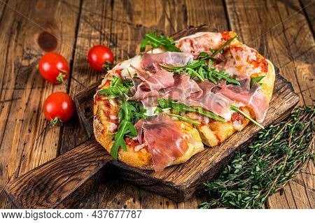 Sliced Pizza With Prosciutto Parma Ham, Arugula And Parmesan Cheese On A Wooden Board. Wooden Backgr
