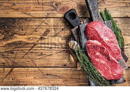 Raw Shoulder Top Blade Beef Meat Steaks On A Wooden Butcher Board With Herbs. Wooden Background. Top