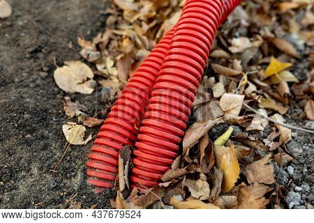 Red Corrugated Hose For Electrical Wiring Is Dug Into Ground. Underground Electricity Supply