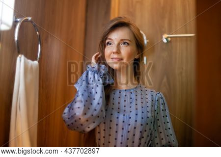 Portrait Of Young Beautiful Woman In Dress Doing Make-up, Touch Her Hair Standing Near Mirror In The