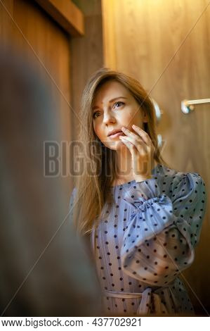 Portrait Of Young Beautiful Woman In Dress Doing Make-up, Touch Her Lips Standing Near Mirror In The