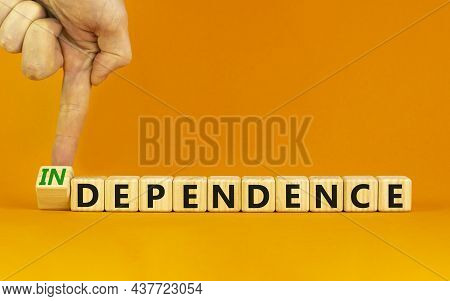 Dependence Or Independence Symbol. Businessman Turns A Cube And Changes The Word 'dependence' To 'in