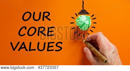 Our Core Values Symbol. Businessman Writing Words 'our Core Values', Isolated On Beautiful Orange Ba