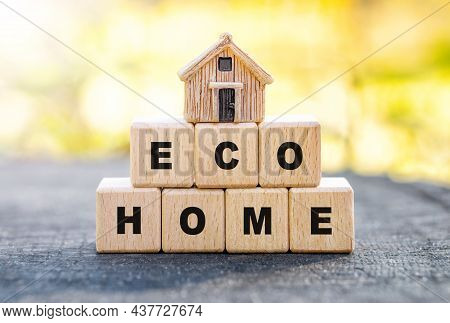 Small Toy House Standing On Wooden Letter Blocks Reading Eco Home Against A Blurred Autumn Forest Ba