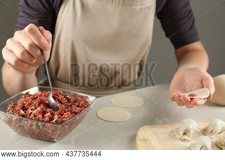 Woman Putting Gyoza Filling In Center Of Dough Wrapper At Light Table, Closeup