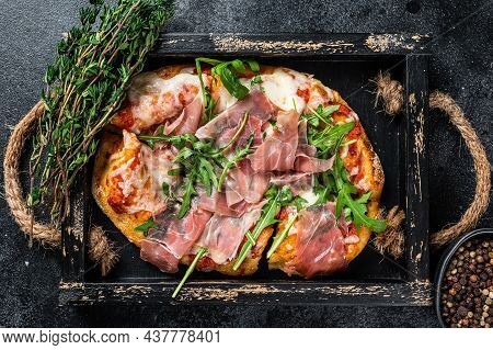 Italian Pizza With Prosciutto Parma Ham, Arugula Salad And Cheese In A Rustic Wooden Tray. Black Bac