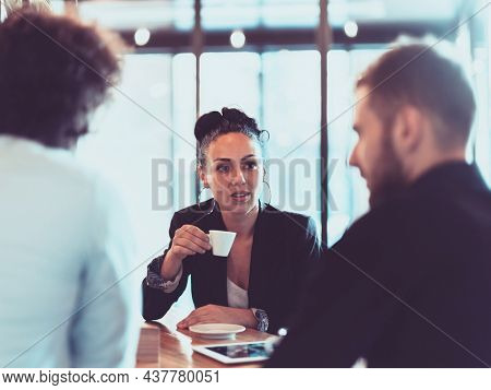 A group of business people on a coffee break use laptops, tablets and smartphones while discussing new business projects. 