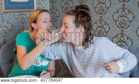 Young Women In Pajamas Celebrate And Drink Champagne In Crystal Glasses On The Bruderschaft.
