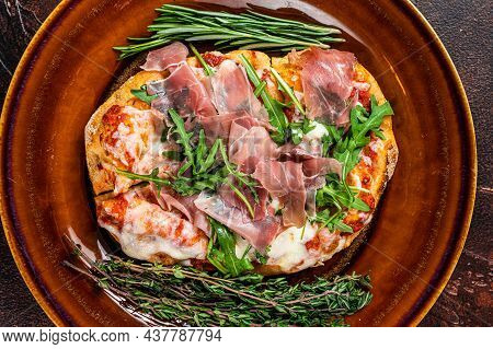 Pizza With Prosciutto Parma Ham, Arugula Salad And Parmesan Cheese In A Rustic Plate. Wooden Backgro
