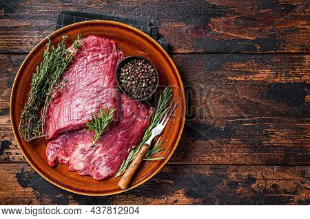 Two Flap Or Flank Raw Beef Steaks On A Rustic Plate With Herbs. Dark Wooden Background. Top View. Co