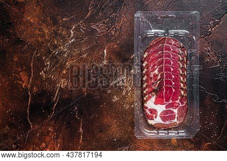 Italian Sliced Cured Coppa Meat In Vacuum Packaging. Dark Background. Top View. Copy Space